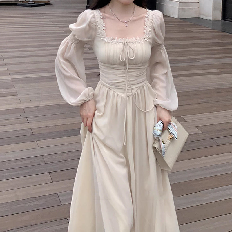 Person wearing a beige dress with puffed sleeves on a wooden floor.