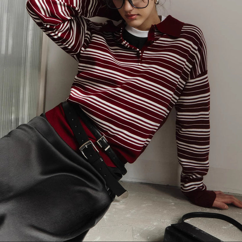 Person wearing a red and white striped sweater with a high collar, sitting on a surface.