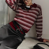 Person wearing a red and white striped sweater with a high collar, sitting on a surface.