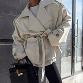 Person wearing a beige trench coat with a black handbag in an urban setting
