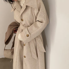 Beige trench coat worn by a person against a neutral background
